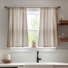 a kitchen sink under a window with curtains