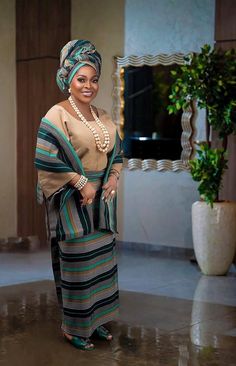 a woman standing in front of a mirror wearing a striped dress and headwrap