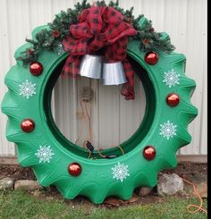 a green christmas wreath with snowflakes and bells on the side of a building