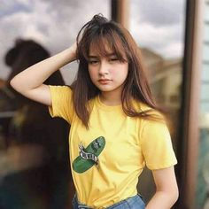 a young woman in a yellow shirt is posing for the camera with her hand on her head