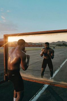 two men standing in front of a mirror with one man holding a boxing glove to his face