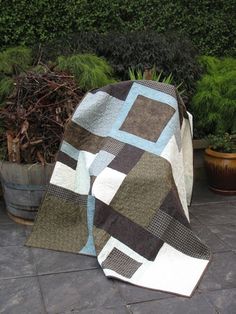 a quilted blanket sitting on the ground next to some potted plants