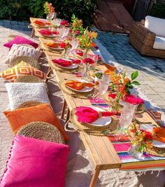 a long table set up with plates and place settings for an outdoor dinner or brunch