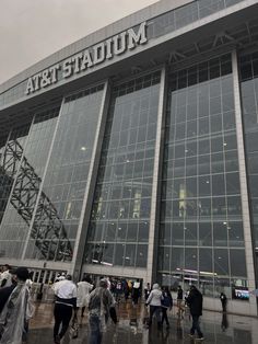 people are walking around outside the art stadium in the rain with their umbrellas up