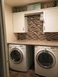 a washer and dryer in a laundry room with cabinets above them that are built into the wall