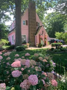 a pink house surrounded by flowers and trees