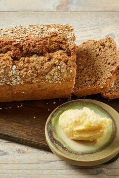 a loaf of bread sitting on top of a wooden cutting board next to a bowl of butter