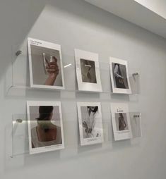 a wall that has some pictures on it with glass shelves above them and one person holding a cell phone