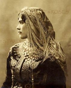 an old photo of a woman with long hair and braids on her head, looking off to the side