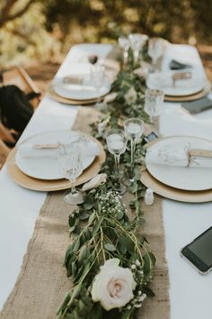 the table is set with white plates and place settings