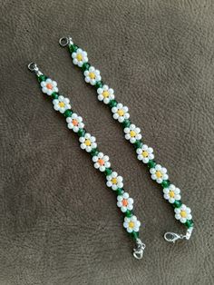 two white and yellow flowers are attached to a green lanyard with silver clasps