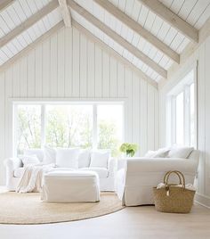 a living room with white furniture and wood floors in the center, along with large windows