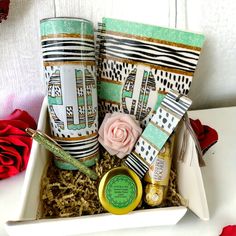 two coffee mugs in a gift box with roses and other things to put on them