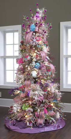 a decorated christmas tree in the corner of a room with two windows and a purple mat on the floor