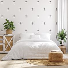 a bed with white sheets and pillows next to a potted plant