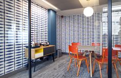 an office with blue and white wallpaper, orange chairs and a table in the middle