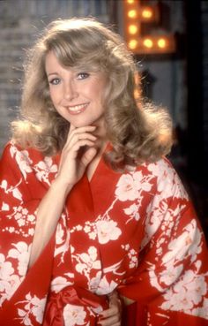 a woman with blonde hair wearing a red and white flowered dress posing for a photo