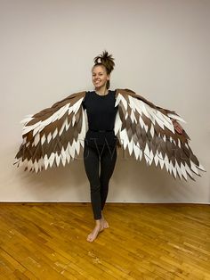 a woman standing in front of a wall holding an owl wings costume