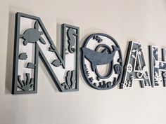 the word noah is made up of metal letters and animals on white wall with black lettering