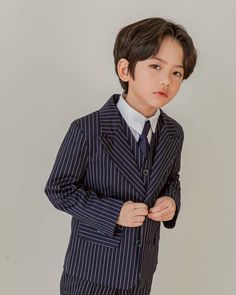 a young boy in a suit and tie poses for a photo with his hands on his hips