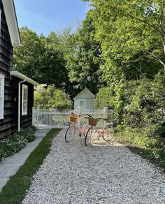 a bicycle parked in front of a house next to a white picket fence and trees