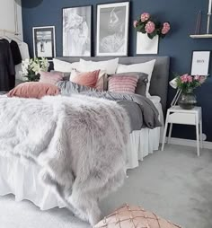 a bedroom with blue walls and white bedding has pink flowers on the nightstands