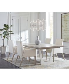 a dining room table with white chairs and a vase