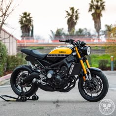 a yellow and black yamaha motorcycle parked on the side of the road with palm trees in the background