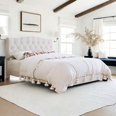 a white bed sitting in the middle of a bedroom next to a dresser and window