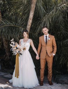 a bride and groom are holding hands in front of some palm trees at their wedding