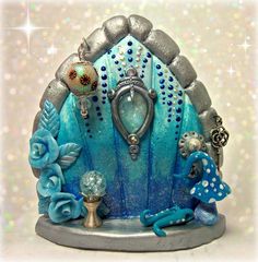 a blue and silver fairy house with lots of decorations on it's front door