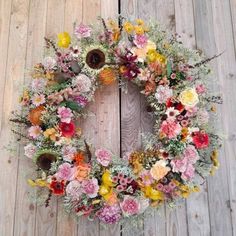 a wreath with flowers is hanging on a wooden wall