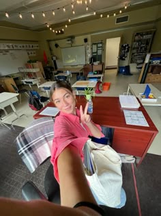 a woman sitting at a desk giving the peace sign