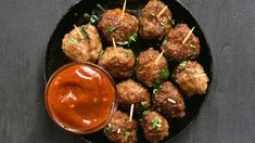 meatballs with toothpicks and ketchup in a black bowl on a table