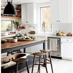 an image of a kitchen setting with white cabinets and wood counter tops, stools in the foreground