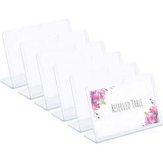 four clear acrylic place cards with floral designs on the front and back sides