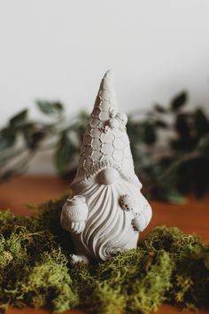 a white gnome figurine sitting on top of moss