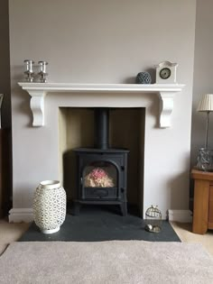 a living room with a fire place next to a vase and lamp on the floor