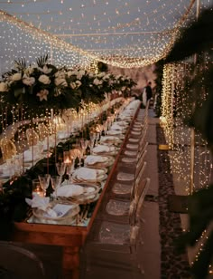 a long table is set up with white flowers and greenery for an outdoor dinner