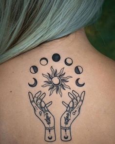 the back of a woman's neck with two hands holding sun and moon tattoos on it