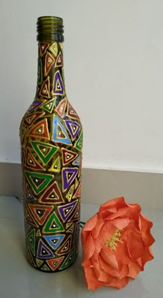 there is a vase with designs on it next to an orange flower and a white wall