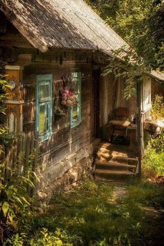 an old log cabin in the woods with steps leading up to it's door