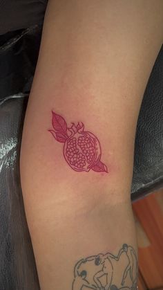 a small pomegranate tattoo on the arm