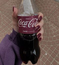 a woman holding up a bottle of coca cola