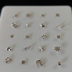 several pairs of silver earrings are displayed on a white surface with black dots and stars