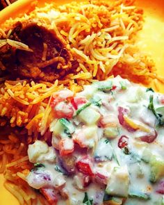 a yellow plate topped with rice, meat and veggies next to other foods