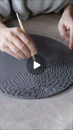 a person is using a pencil to draw on a plate with an intricate design in the center