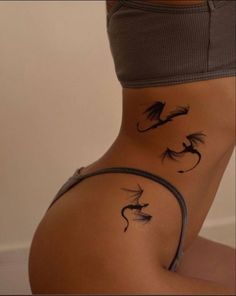 a woman's stomach with tattoos on her body and two birds flying over it