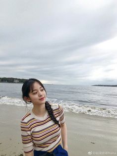 a woman sitting on top of a sandy beach next to the ocean