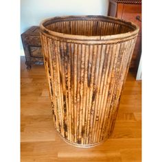 a large bamboo trash can sitting on top of a wooden floor next to a dresser